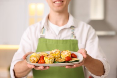 Photo of Man with freshly grilled vegetables in kitchen, closeup