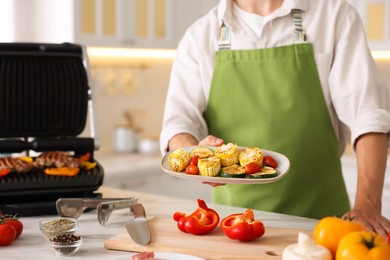 Photo of Man with freshly grilled vegetables in kitchen, closeup