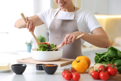 Photo of Smiling woman cooking at table in kitchen, closeup