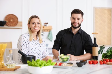 Photo of Happy couple cooking together at table in kitchen
