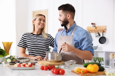 Photo of Happy couple cooking together at table in kitchen