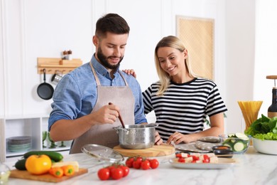 Photo of Happy couple cooking together at table in kitchen