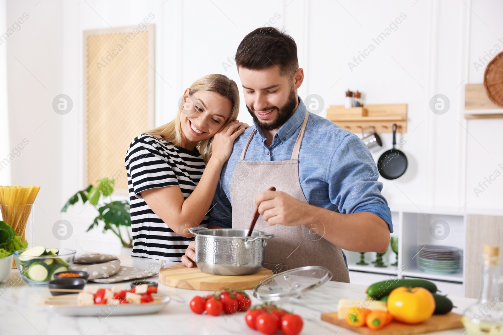 Photo of Happy couple cooking together at table in kitchen