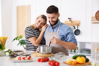 Photo of Happy couple cooking together at table in kitchen