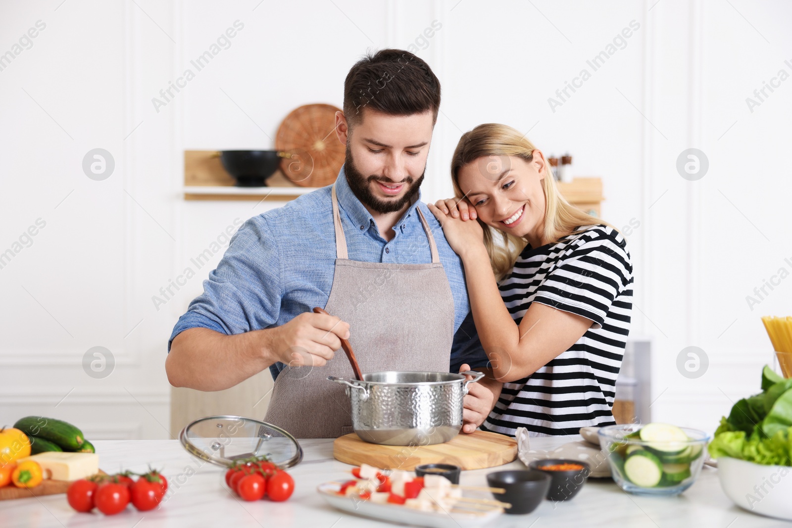 Photo of Happy couple cooking together at table in kitchen