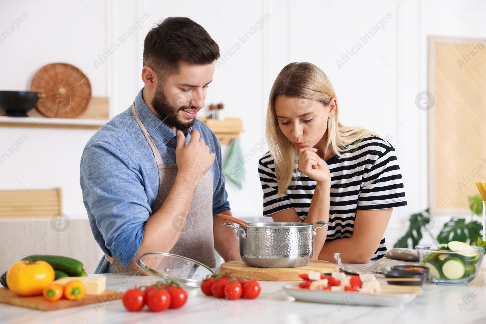 Photo of Couple cooking together at table in kitchen