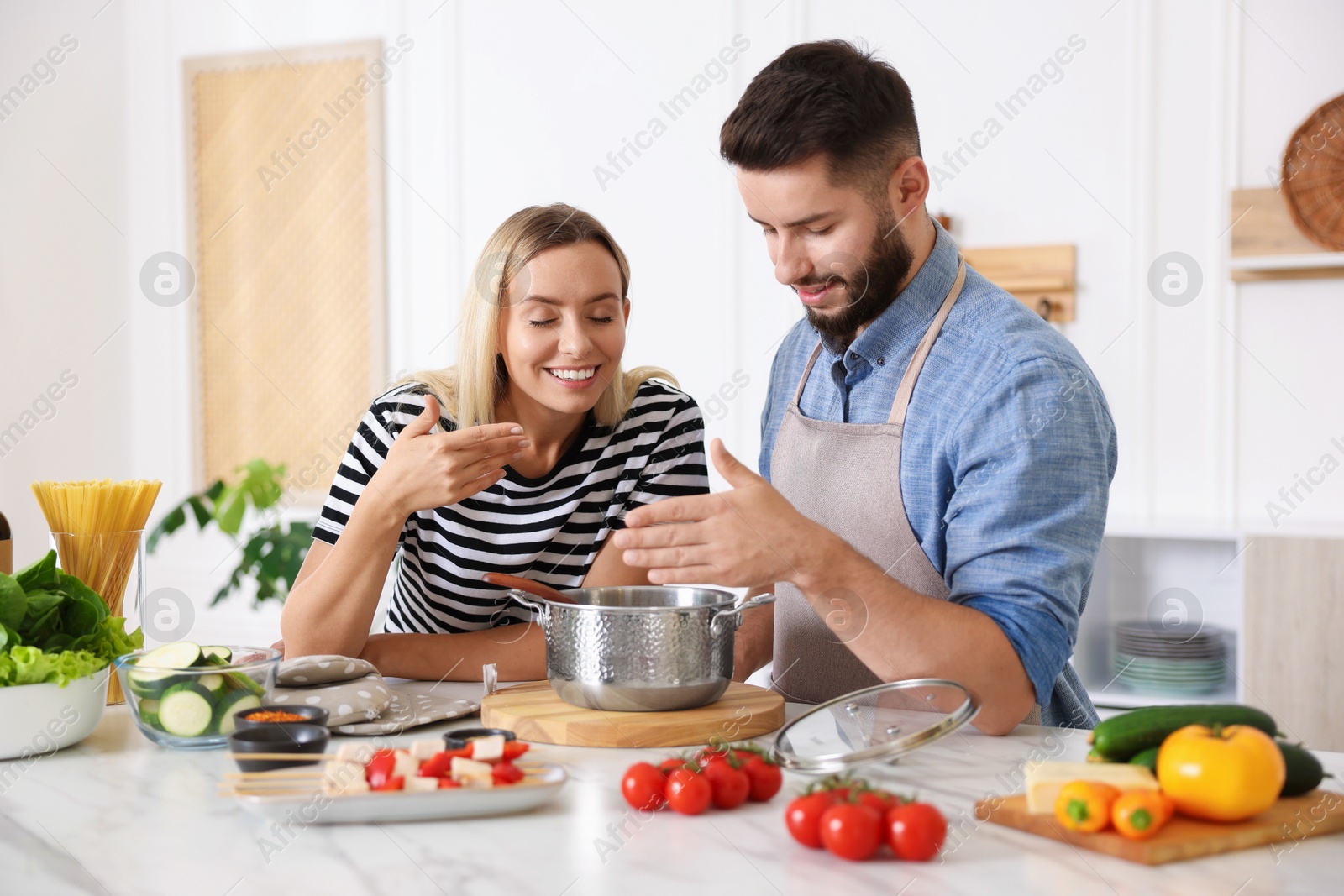 Photo of Happy couple cooking together at table in kitchen