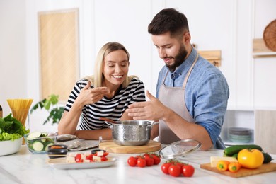 Photo of Happy couple cooking together at table in kitchen