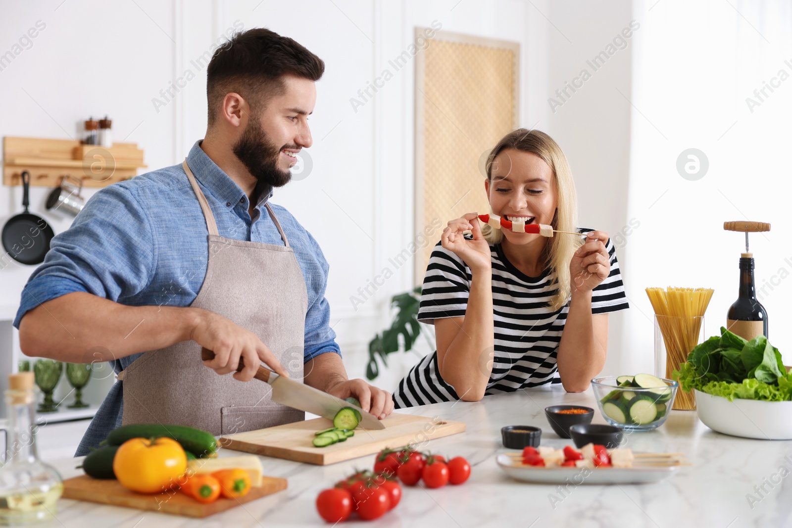 Photo of Happy couple cooking together at table in kitchen