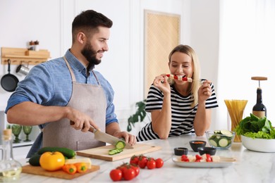 Photo of Happy couple cooking together at table in kitchen