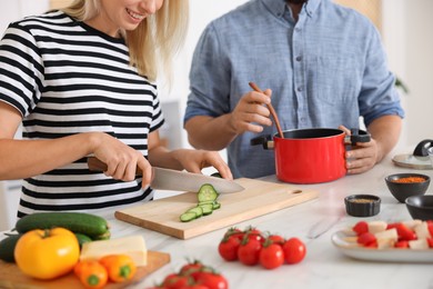 Photo of Couple cooking together at table indoors, closeup