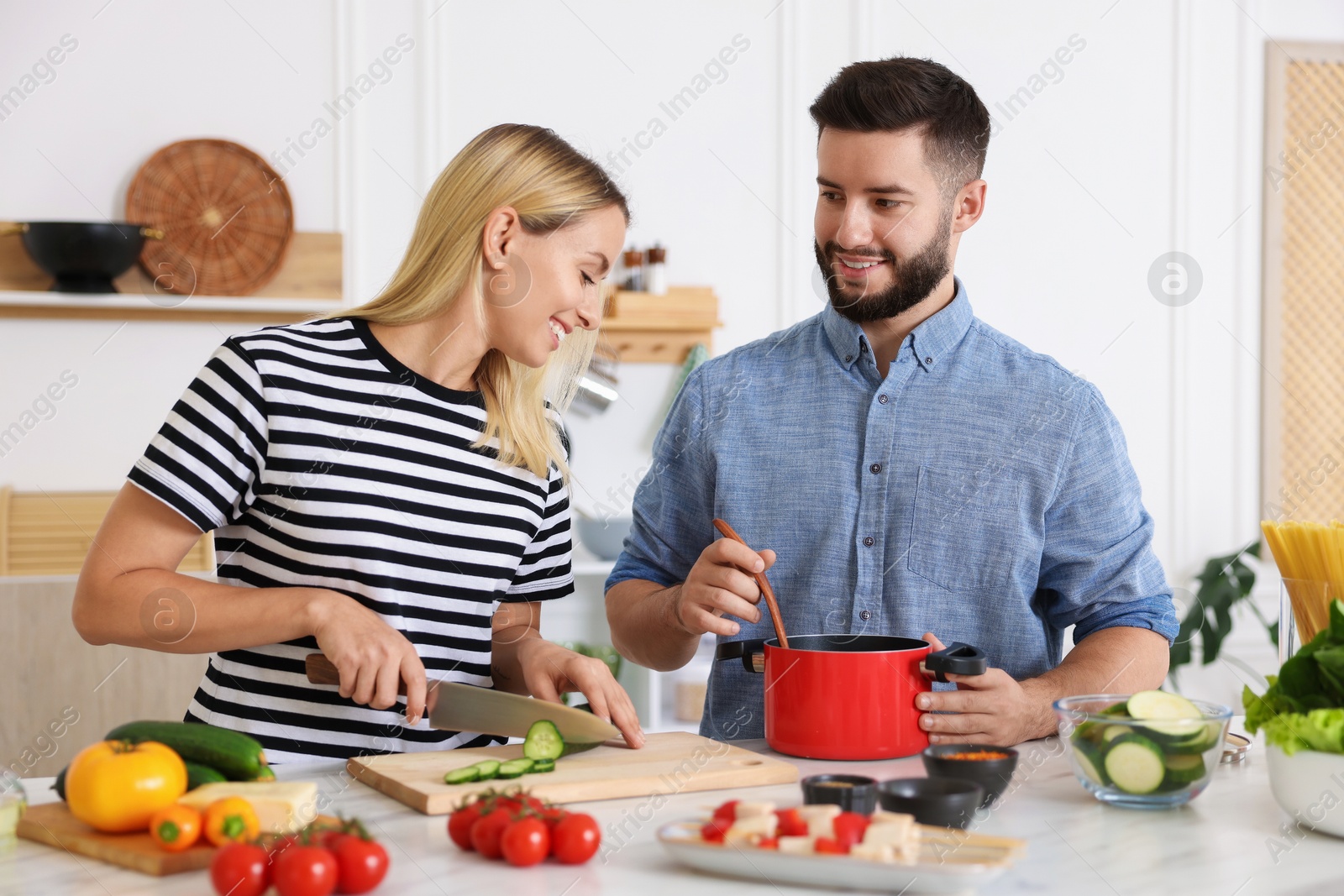 Photo of Happy couple cooking together at table in kitchen