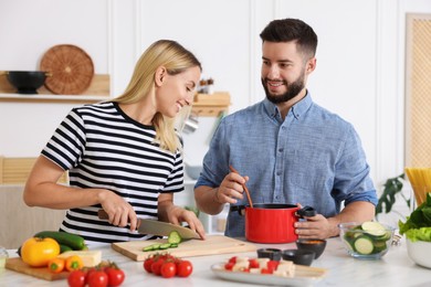 Photo of Happy couple cooking together at table in kitchen