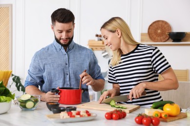 Photo of Happy couple cooking together at table in kitchen