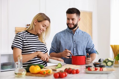 Photo of Happy couple cooking together at table in kitchen