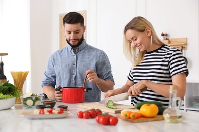 Photo of Happy couple cooking together at table in kitchen