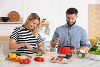 Photo of Happy couple cooking together at table in kitchen