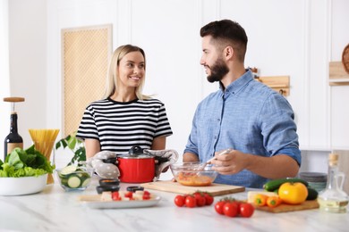 Photo of Happy couple cooking together at table in kitchen