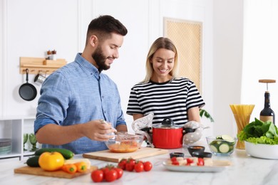 Photo of Happy couple cooking together at table in kitchen
