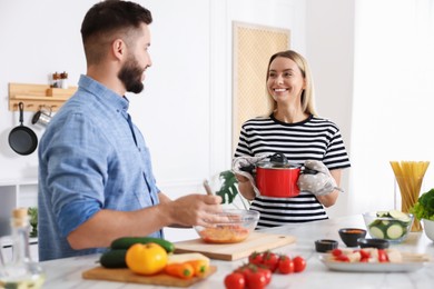 Photo of Happy couple cooking together at table in kitchen