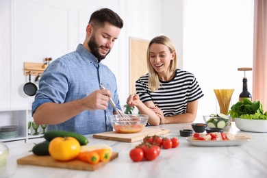 Photo of Happy couple cooking together at table in kitchen