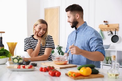 Photo of Happy couple cooking together at table in kitchen
