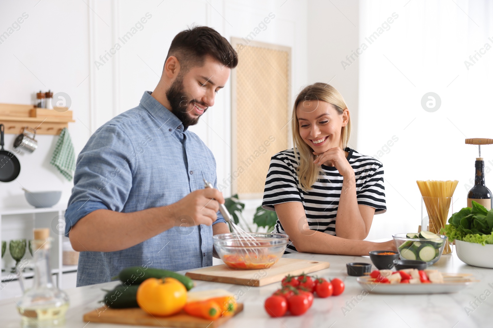 Photo of Happy couple cooking together at table in kitchen