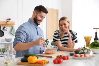 Photo of Happy couple cooking together at table in kitchen