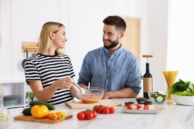 Photo of Happy couple cooking together at table in kitchen