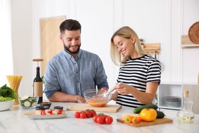 Photo of Happy couple cooking together at table in kitchen