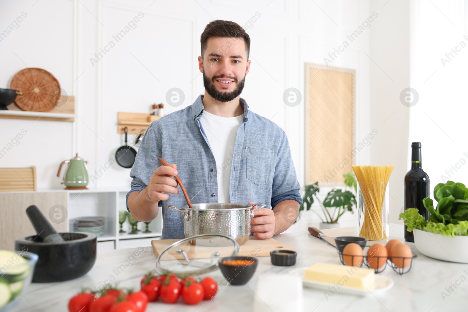 Photo of Smiling man cooking at table in kitchen