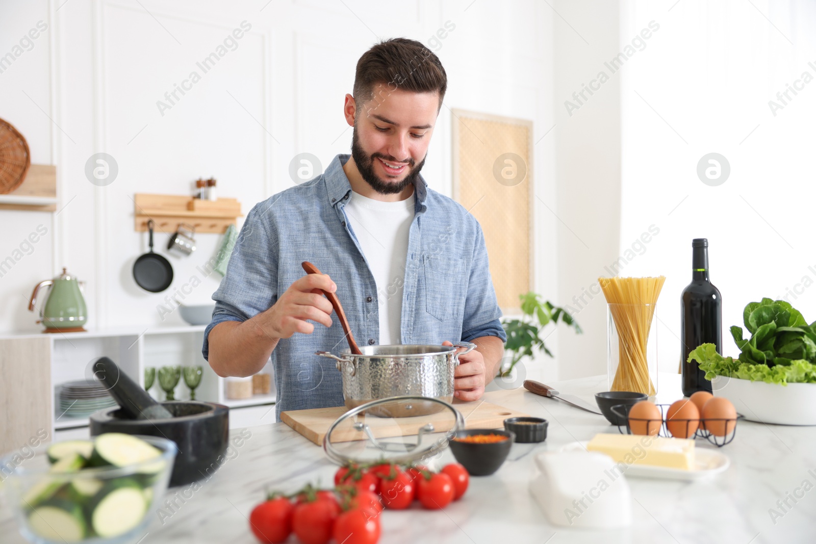 Photo of Smiling man cooking at table in kitchen