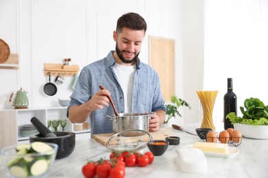 Photo of Smiling man cooking at table in kitchen