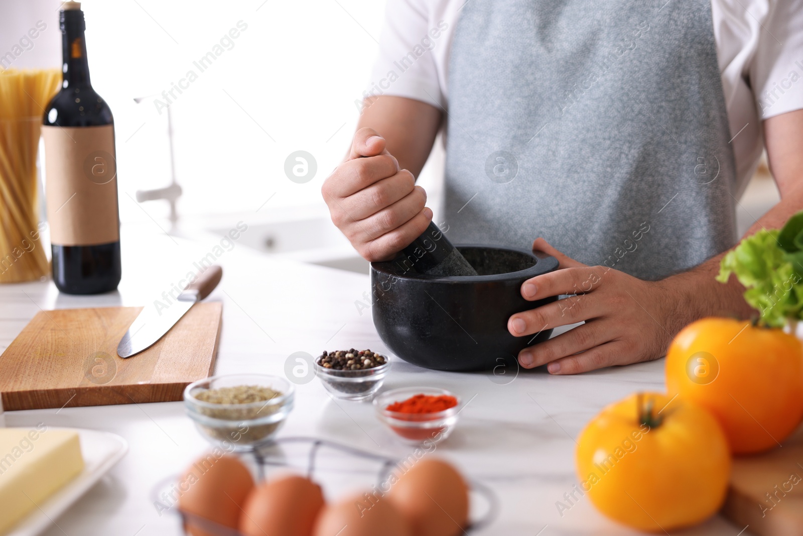 Photo of Man with mortar cooking at table indoors, closeup