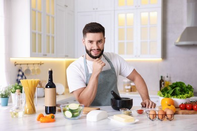 Photo of Smiling man cooking at table in kitchen