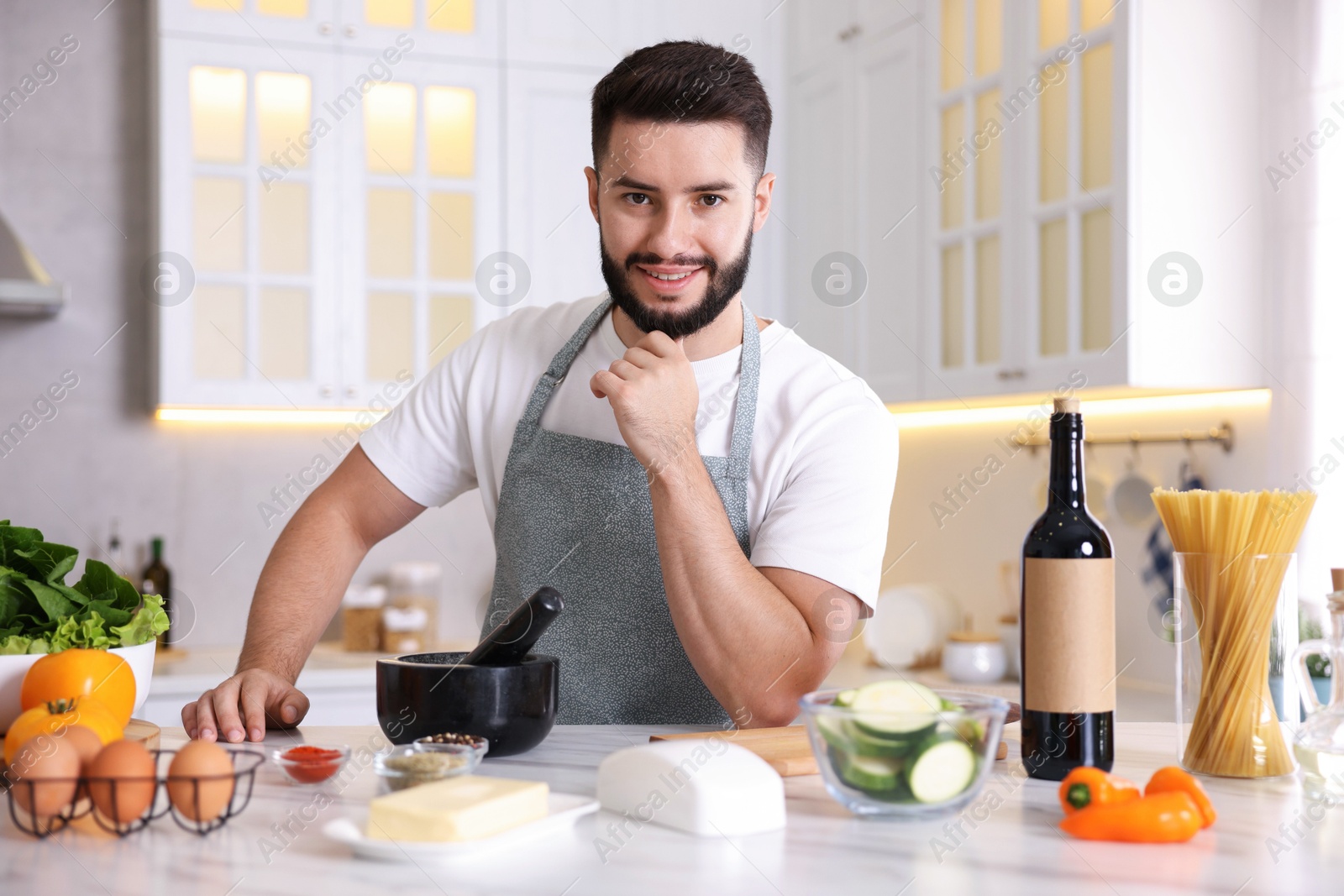 Photo of Portrait of smiling man cooking at table in kitchen