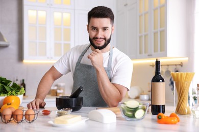 Photo of Portrait of smiling man cooking at table in kitchen
