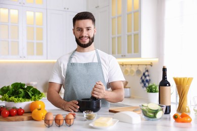 Photo of Smiling man cooking at table in kitchen
