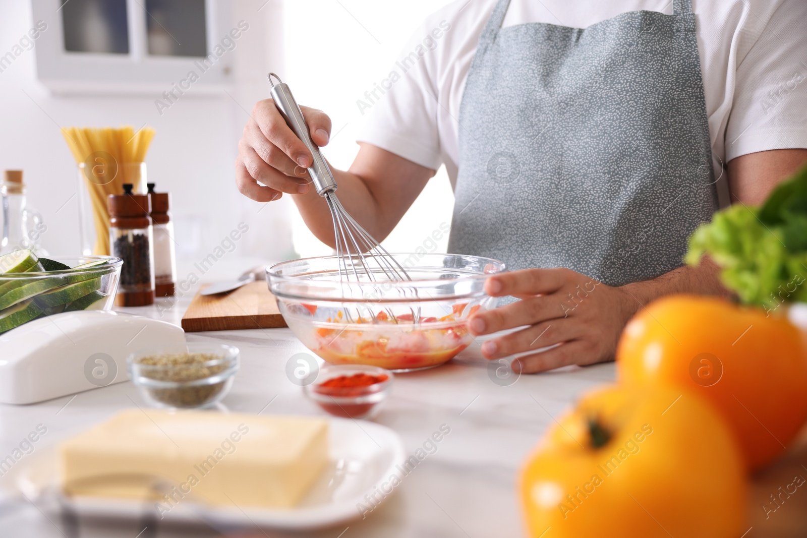 Photo of Man with whisk cooking at table indoors, closeup