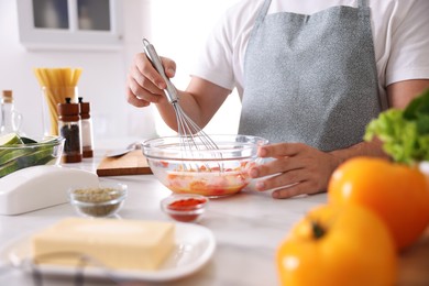 Photo of Man with whisk cooking at table indoors, closeup