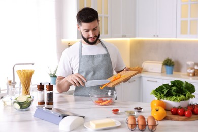Photo of Young man cooking at table in kitchen