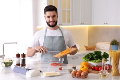 Photo of Smiling man cooking at table in kitchen