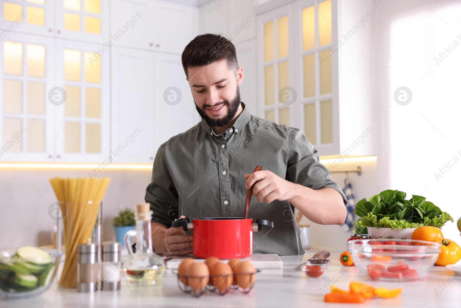 Photo of Smiling man cooking at table in kitchen