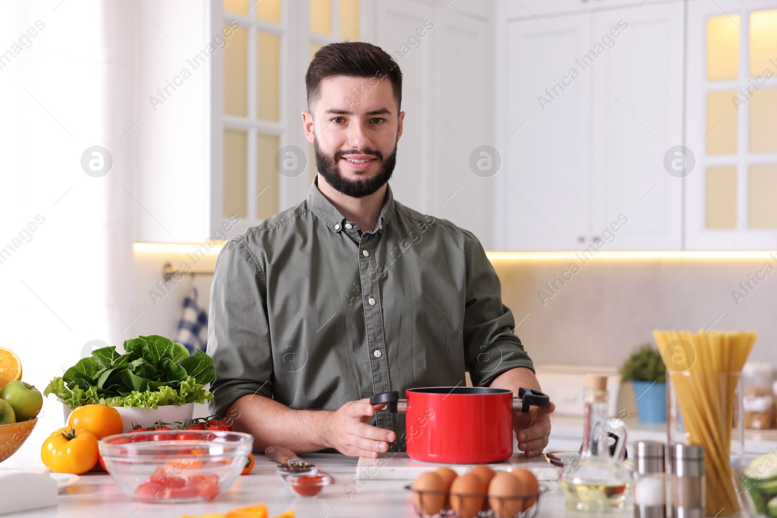 Photo of Smiling man cooking at table in kitchen