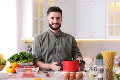 Photo of Smiling man cooking at table in kitchen