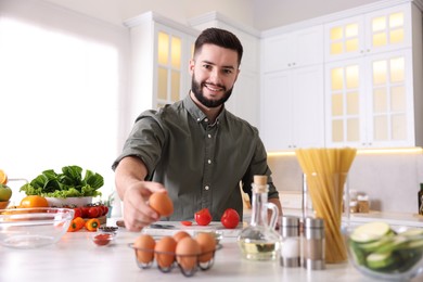 Photo of Smiling man cooking at table in kitchen