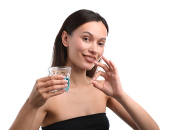 Photo of Young woman with glass of mouthwash showing OK gesture on white background. Oral hygiene