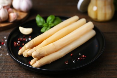 Photo of Pickled asparagus and spices on wooden table, closeup