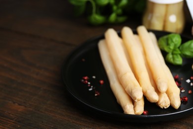 Photo of Pickled asparagus and spices on wooden table, closeup. Space for text