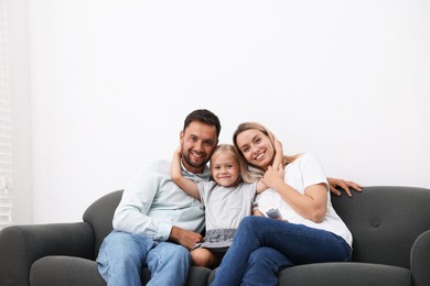 Photo of Happy family with air conditioner remote control on sofa at home